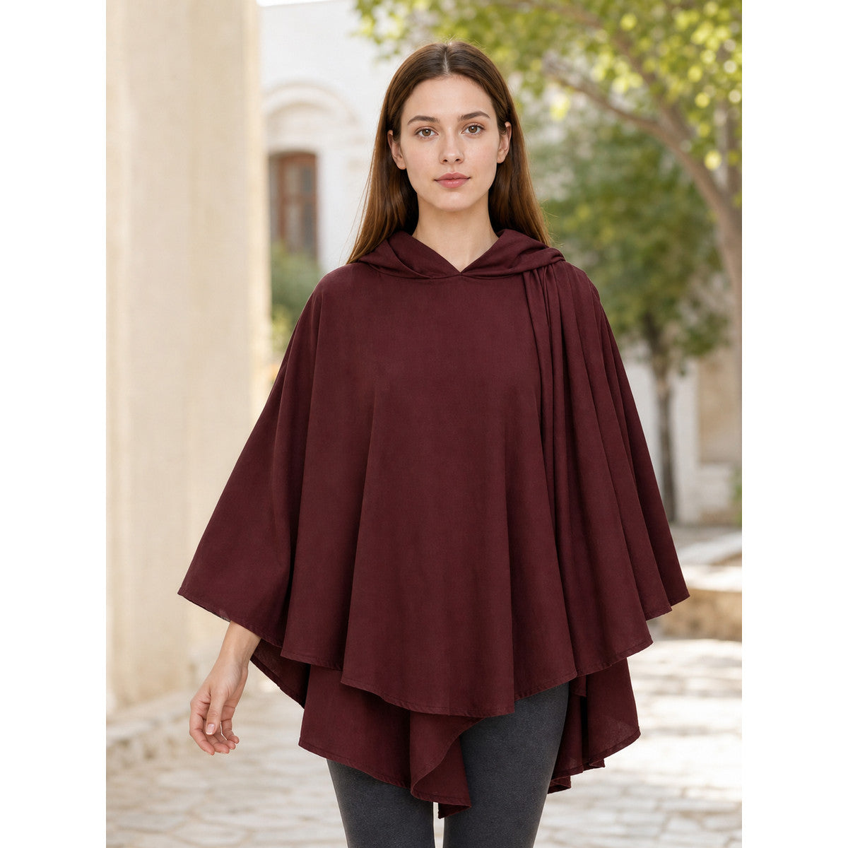 Woman wearing the dark red hooded cape outdoors, front view showing the layered drape