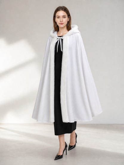 White hooded cape with soft-looking trim and front ties, shown full-length on a model in a styled indoor setting