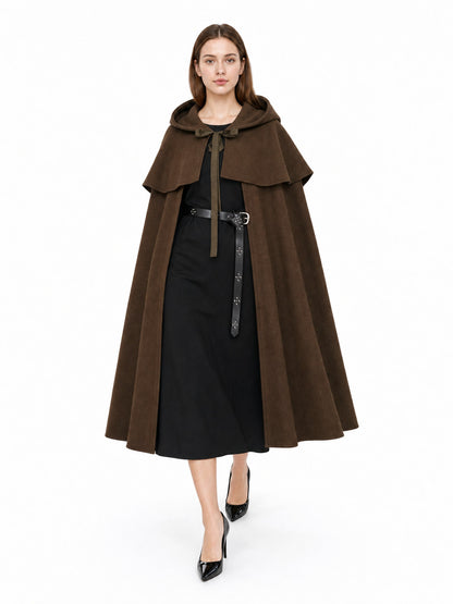 Brown hooded cape with layered shoulder panels and long front ties, shown full-length on a model over black clothing