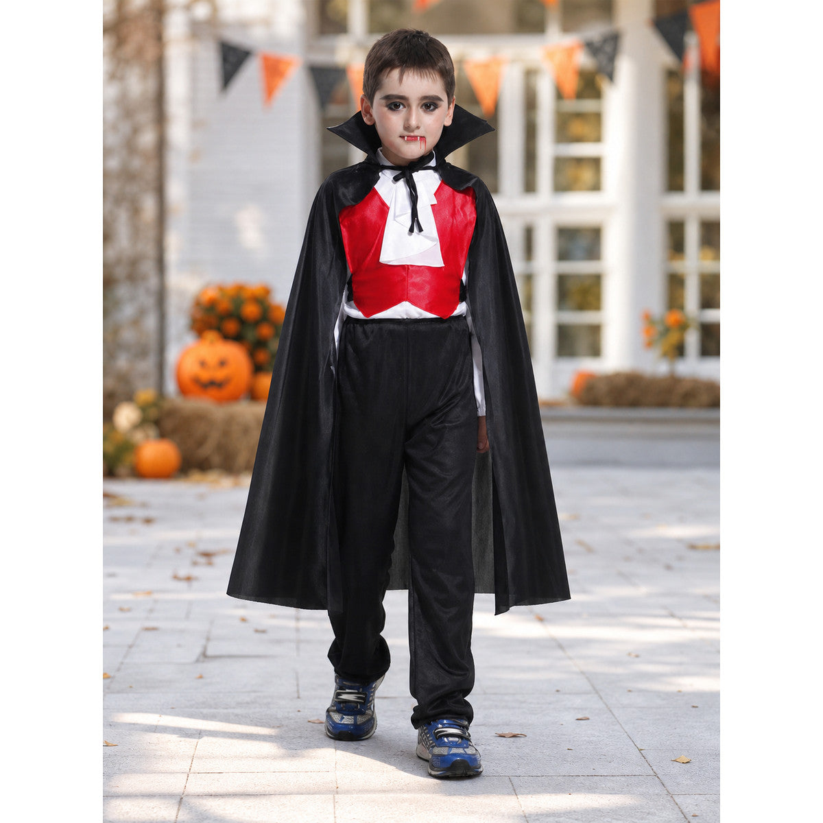 Child wearing the vampire costume with black cape outdoors at Halloween
