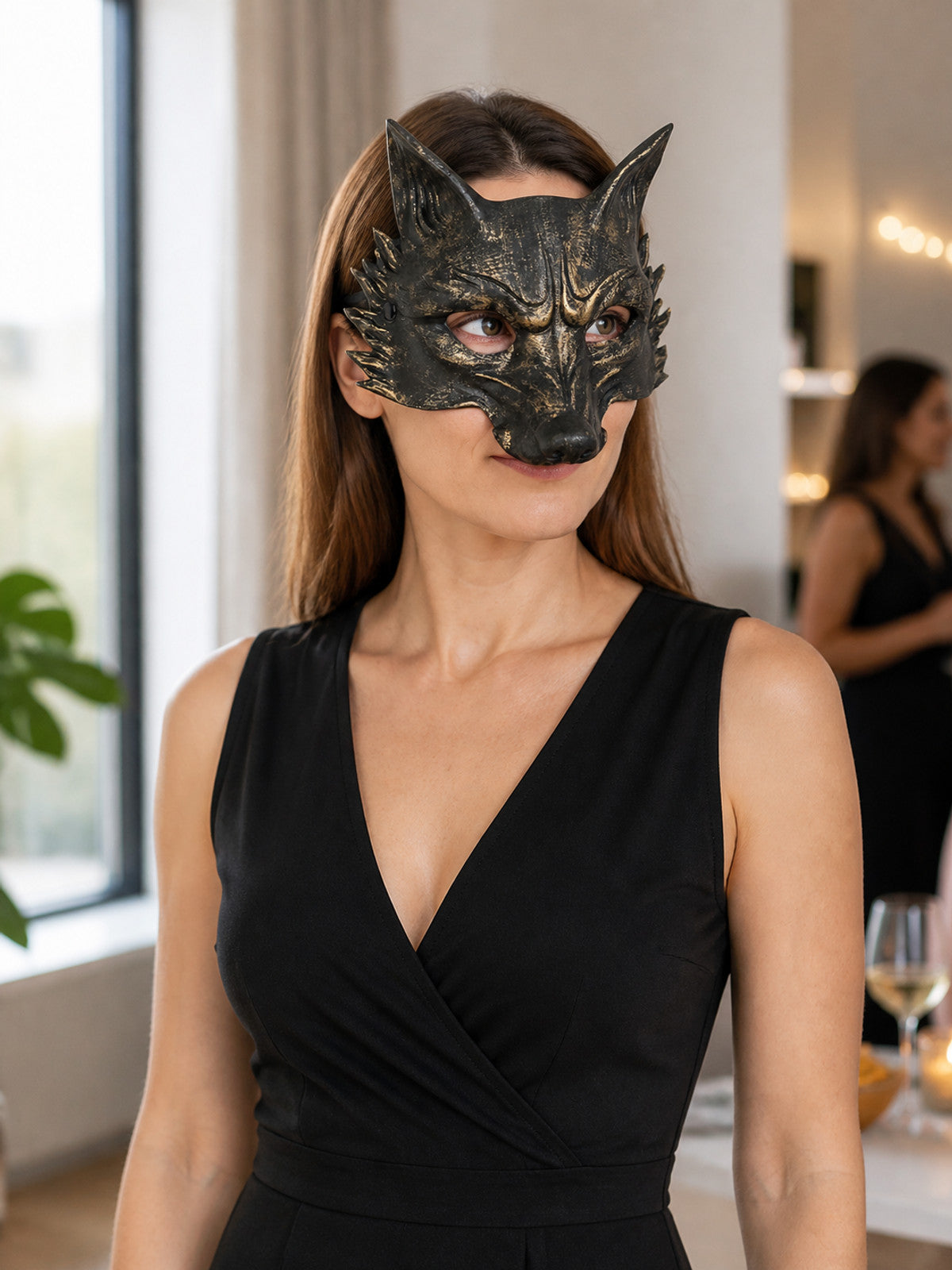Black and gold wolf mask worn in a three-quarter portrait with a dark sleeveless dress