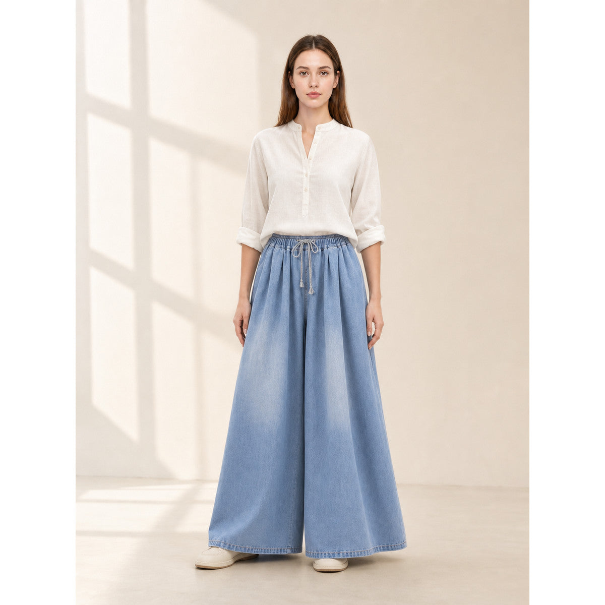 The model features a relaxed style with very wide, full-length legs that create a laid-back silhouette and suit everyday looks. The light blue shade with a subtle denim-like effect makes the piece versatile for warm weather and easy to pair