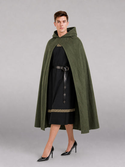 Dark olive hooded cape shown full-body on a model, worn open over a black tunic with a black belt and pointed front clasp