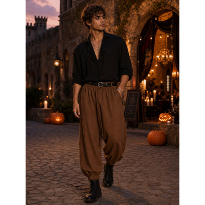 Brown cropped jogger pants with a loose fit and elastic ankle cuffs, styled on a model outdoors with a black shirt and boots