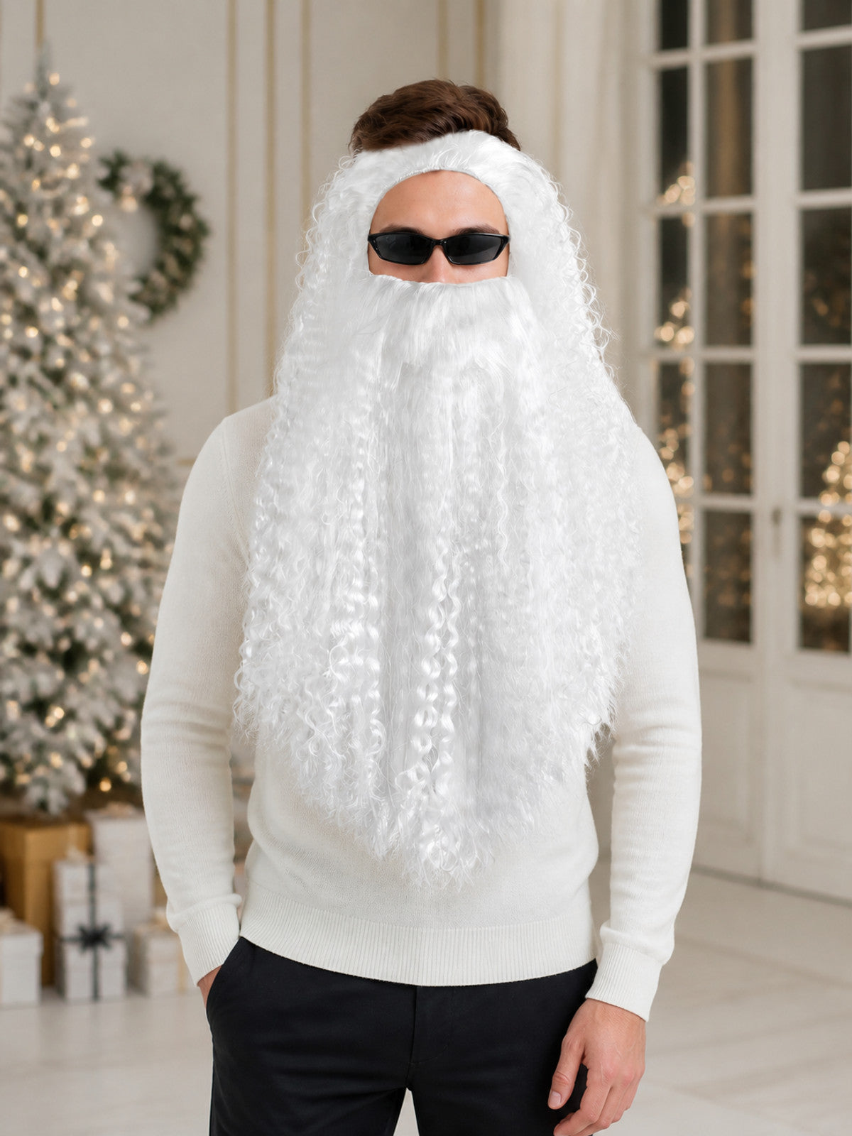 White curly wig and long beard worn by a standing model in a holiday-themed indoor setting