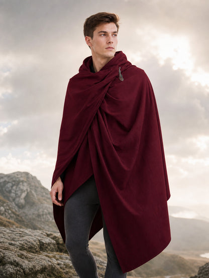 Burgundy hooded cloak with draped front and shoulder fastener, modeled outdoors against a rocky mountain landscape