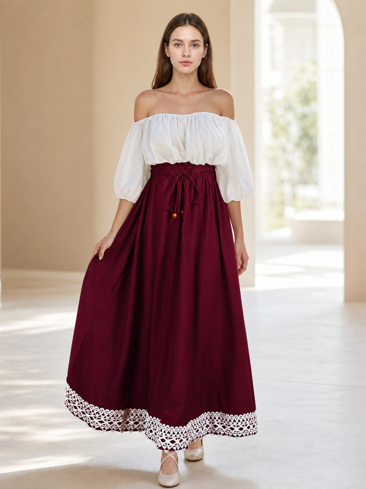 Burgundy A-line skirt shown on a full-body model in a bright interior, with a gathered waist, drawstring, and lace hem