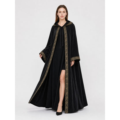Black velvet-like hooded cape with gold patterned trim, shown full-body on a model against a studio background