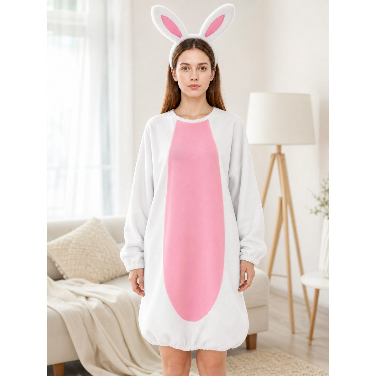 White and pink bunny costume jumpsuit with a plush-looking oval front panel and ear headband, modeled in a living room