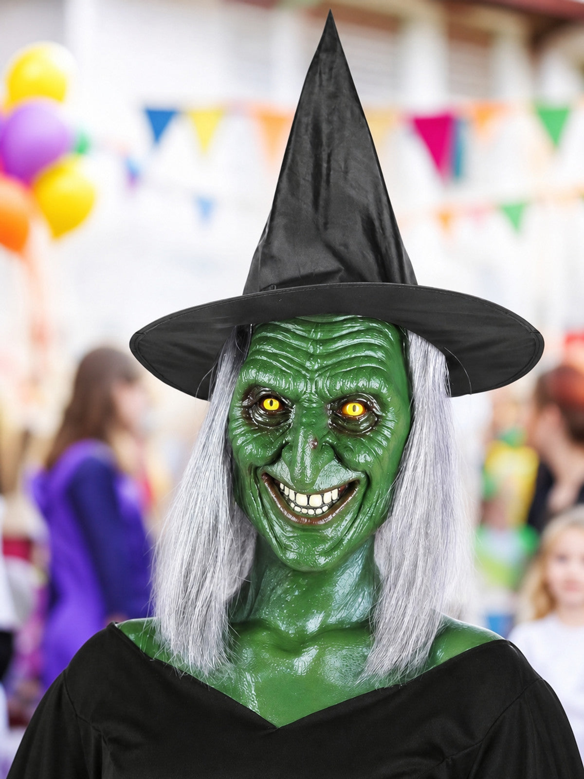 Green witch mask with yellow eyes, gray hair, and black pointed hat, shown on a model in a festive setting