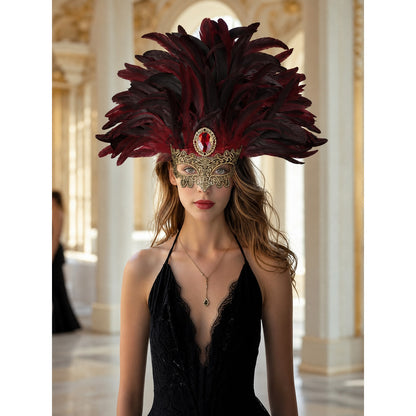 Burgundy and black feathered mask headpiece with gold filigree and red jewel, styled on a model in a black dress indoors