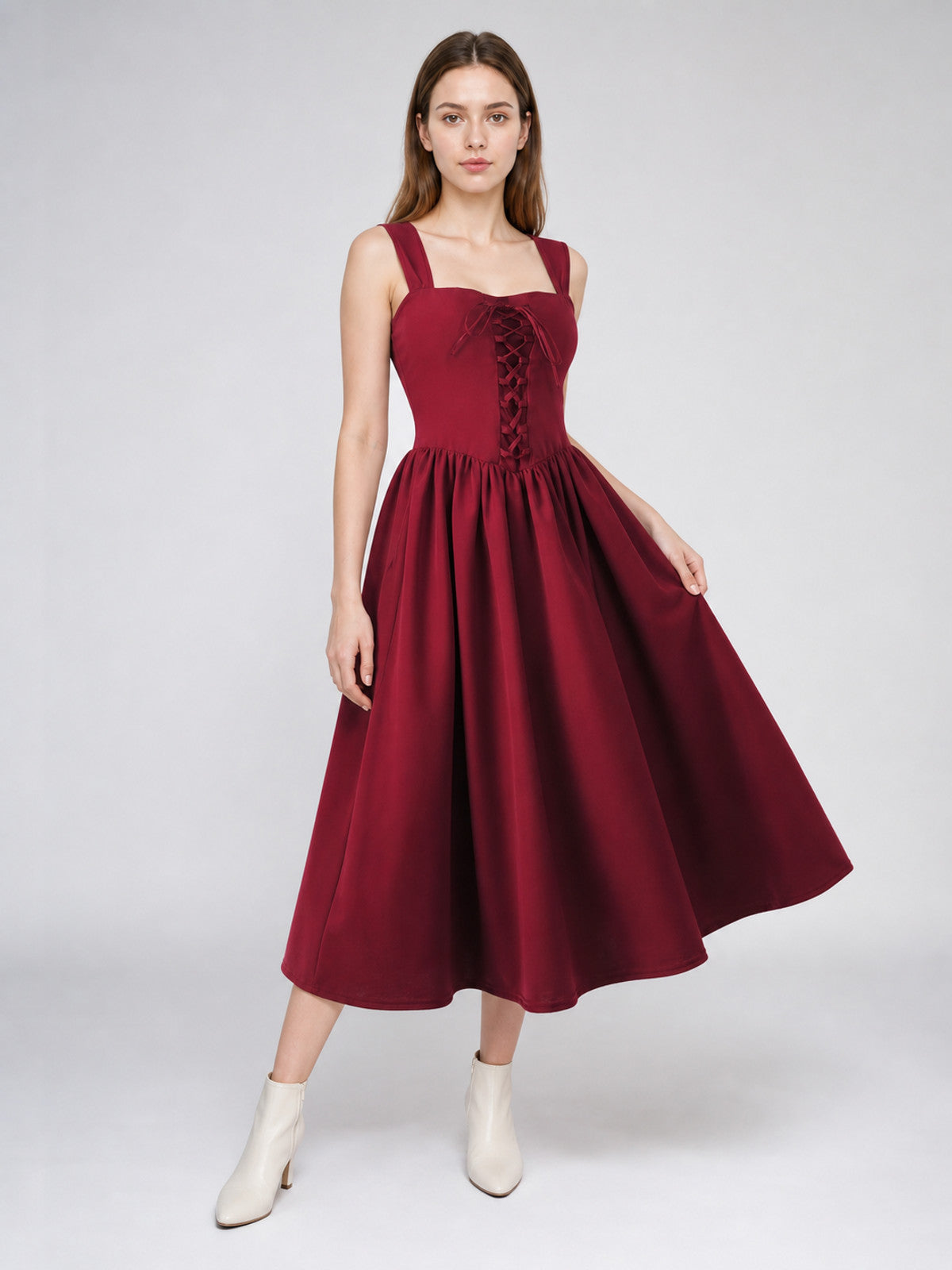 Burgundy long dress with front corset lacing and gathered full skirt, shown on a model holding the skirt to one side