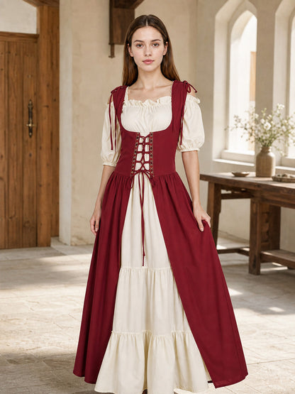 Burgundy and cream dress shown full-body on a model in a rustic interior, with a laced bodice and full skirt