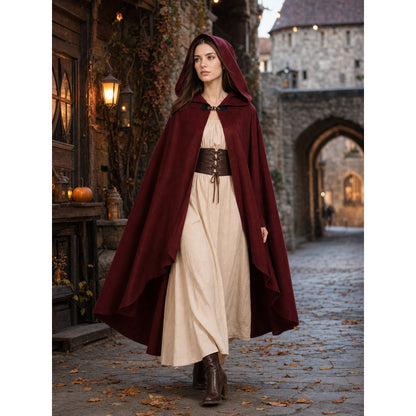 Burgundy hooded cloak with a smooth fabric look and layered hem, modeled over a cream dress in a historic street