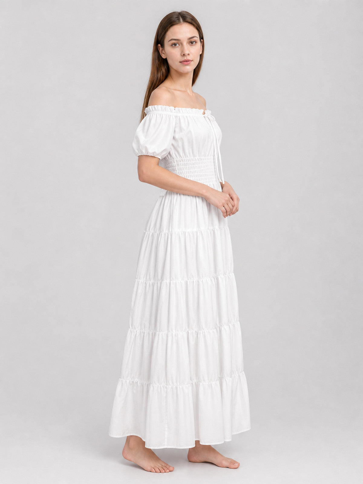 White off-shoulder maxi dress with short puff sleeves, smocked waist, and tiered skirt shown from a three-quarter side view