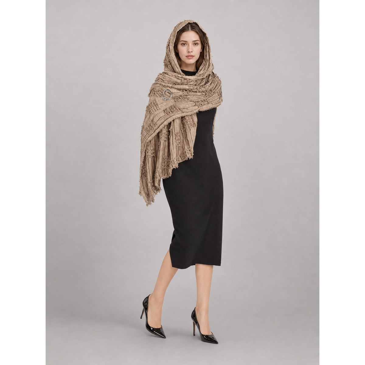 Khaki textured hooded scarf cape with long fringed ends, styled over a black dress on a full-body model