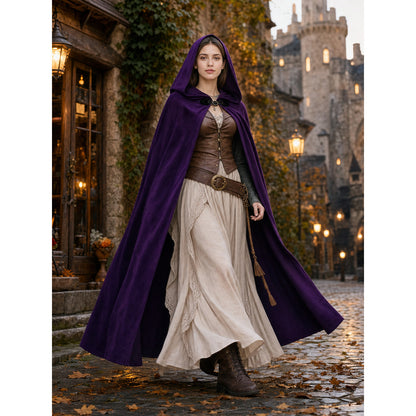 Purple velvet hooded cloak shown full-body on a model in a medieval-style street, worn over a brown bodice and cream skirt