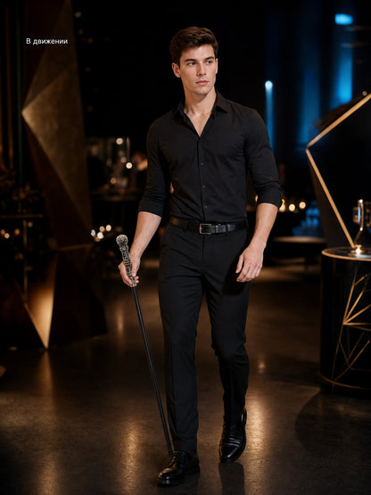 Man in black clothing walking indoors while holding a slim black cane with an ornate silver handle