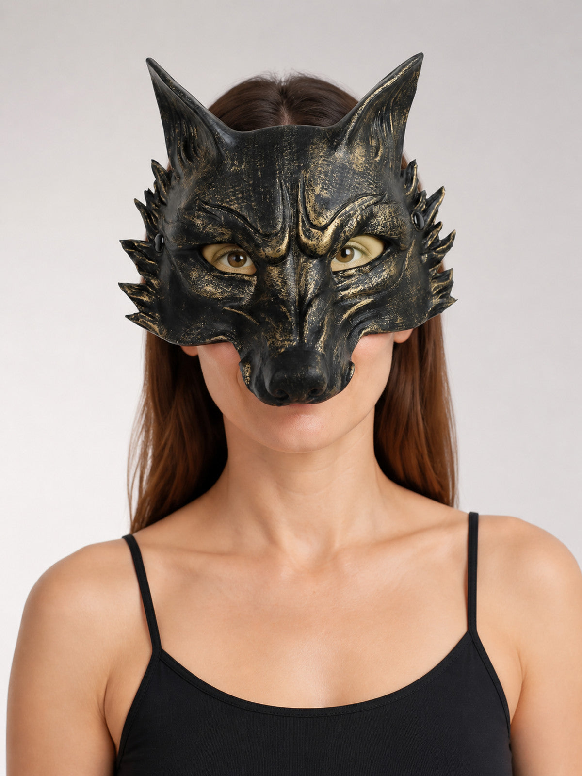 Black wolf mask with gold accents and pointed ears worn in a close-up portrait
