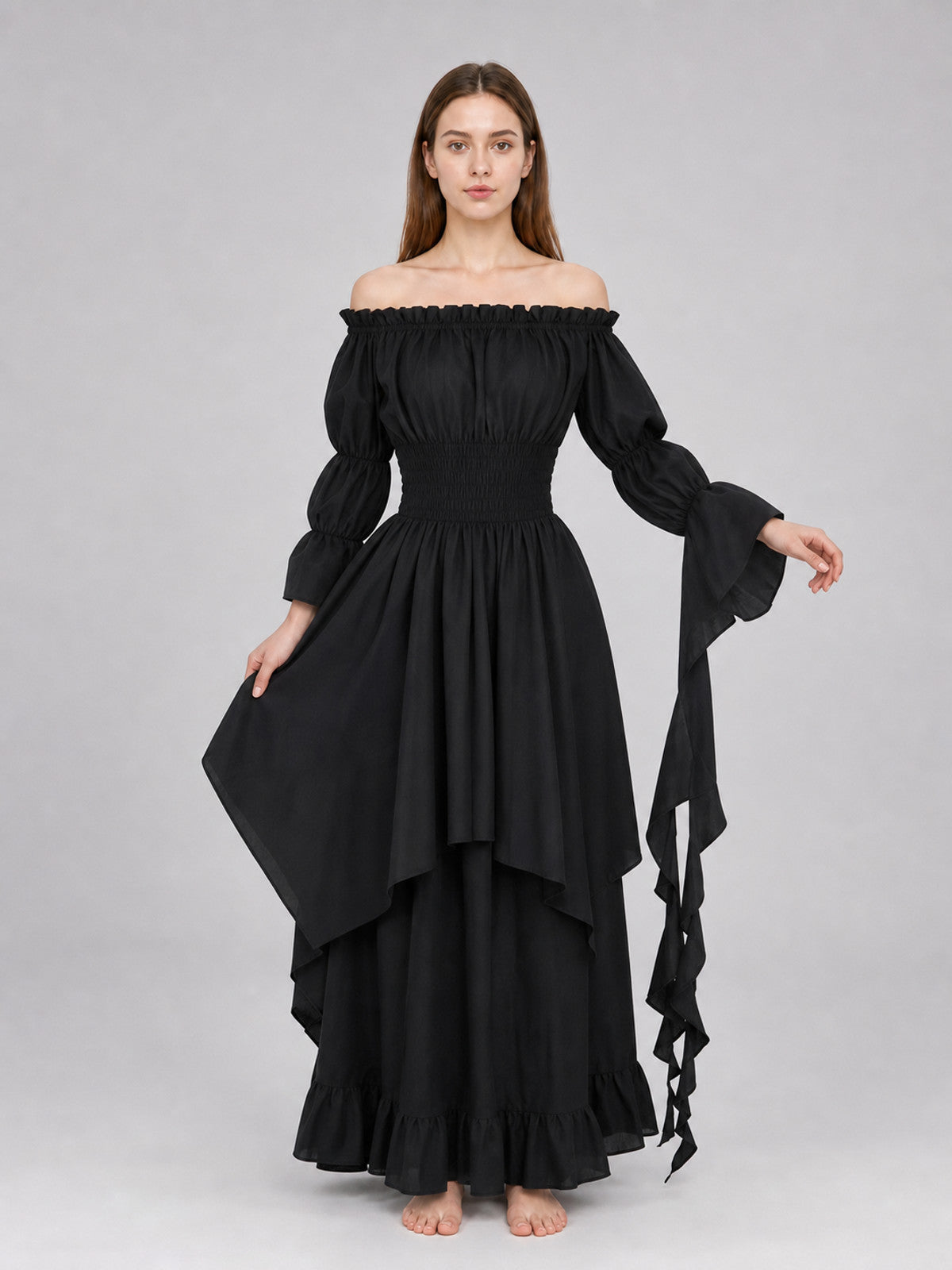 Full-body model wearing a black off-shoulder maxi dress with gathered sleeves, layered ruffled skirt, and long ribbon-like sleeve ties