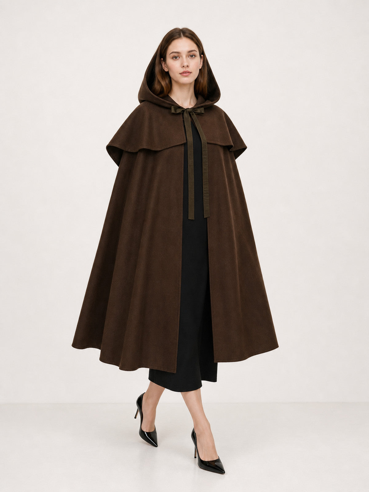 Brown hooded cape with shoulder overlay and front ties, shown full-length on a model over a black dress