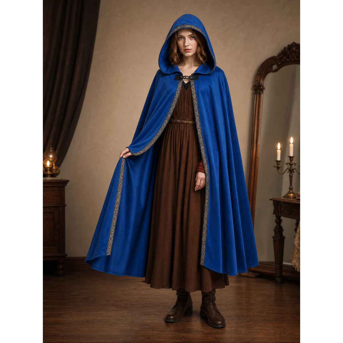 Blue hooded cloak with patterned trim, shown full-length on a model over a brown dress in a candlelit room