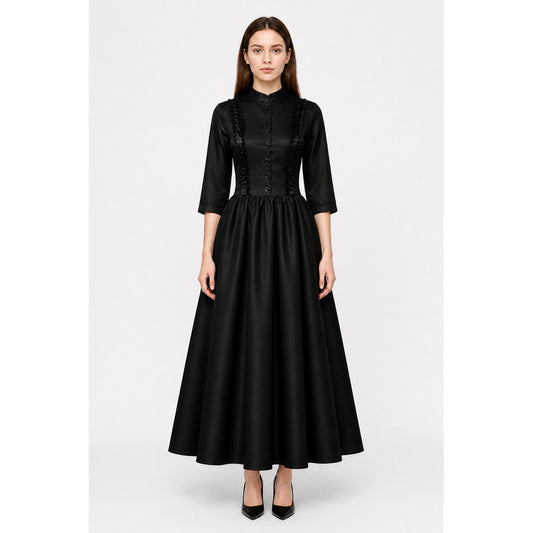 Model wearing a black Victorian gothic dress with high stand collar, front buttons and full floor-length skirt, front view
