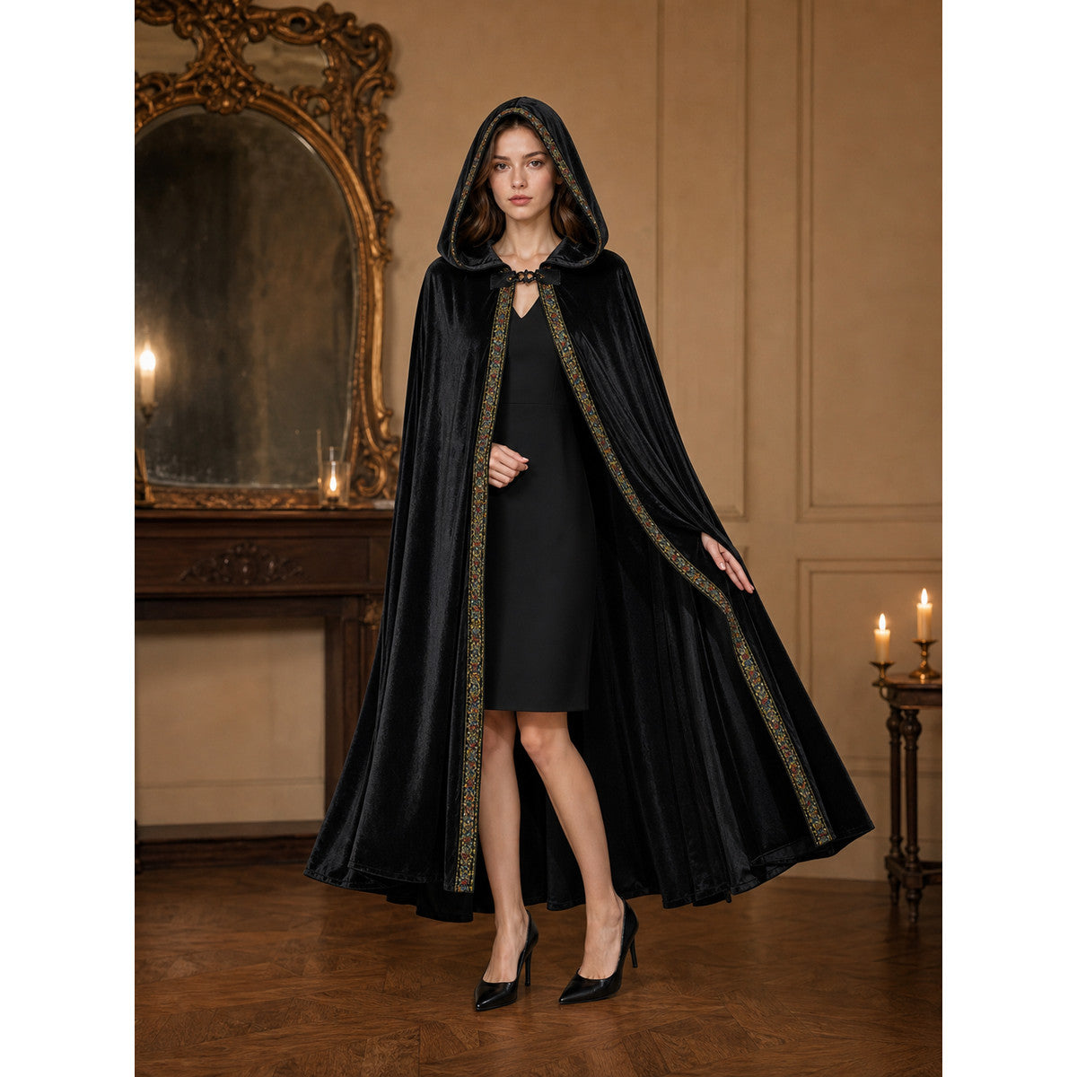 Black velvet-look hooded cloak on a full-body model, with patterned trim along the front and a clasp at the neck