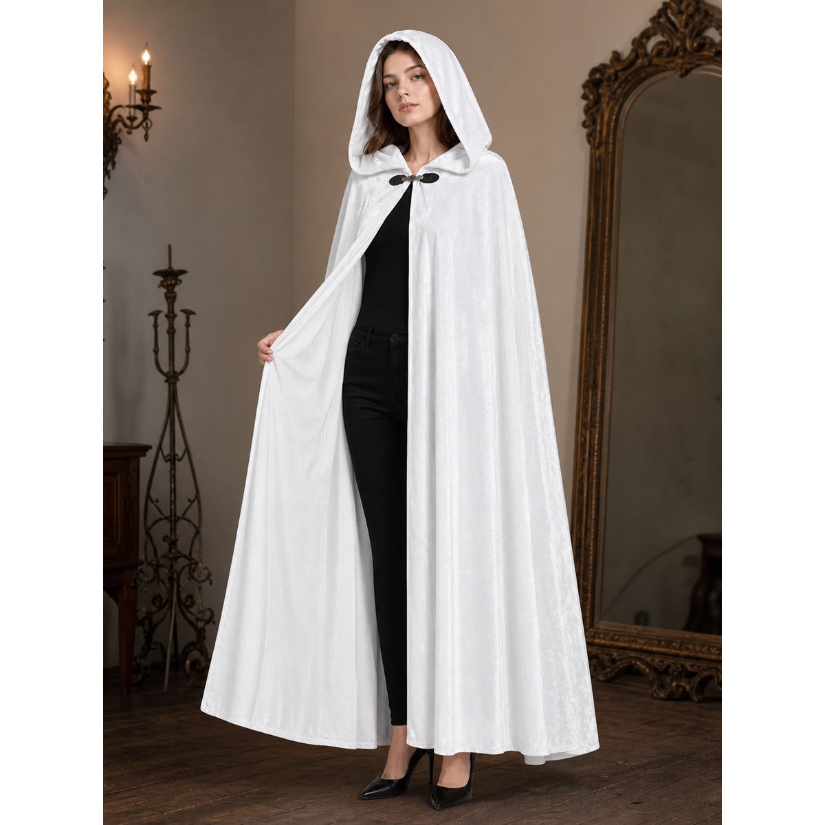 White hooded cape with a black clasp, shown full-length on a model in a styled interior