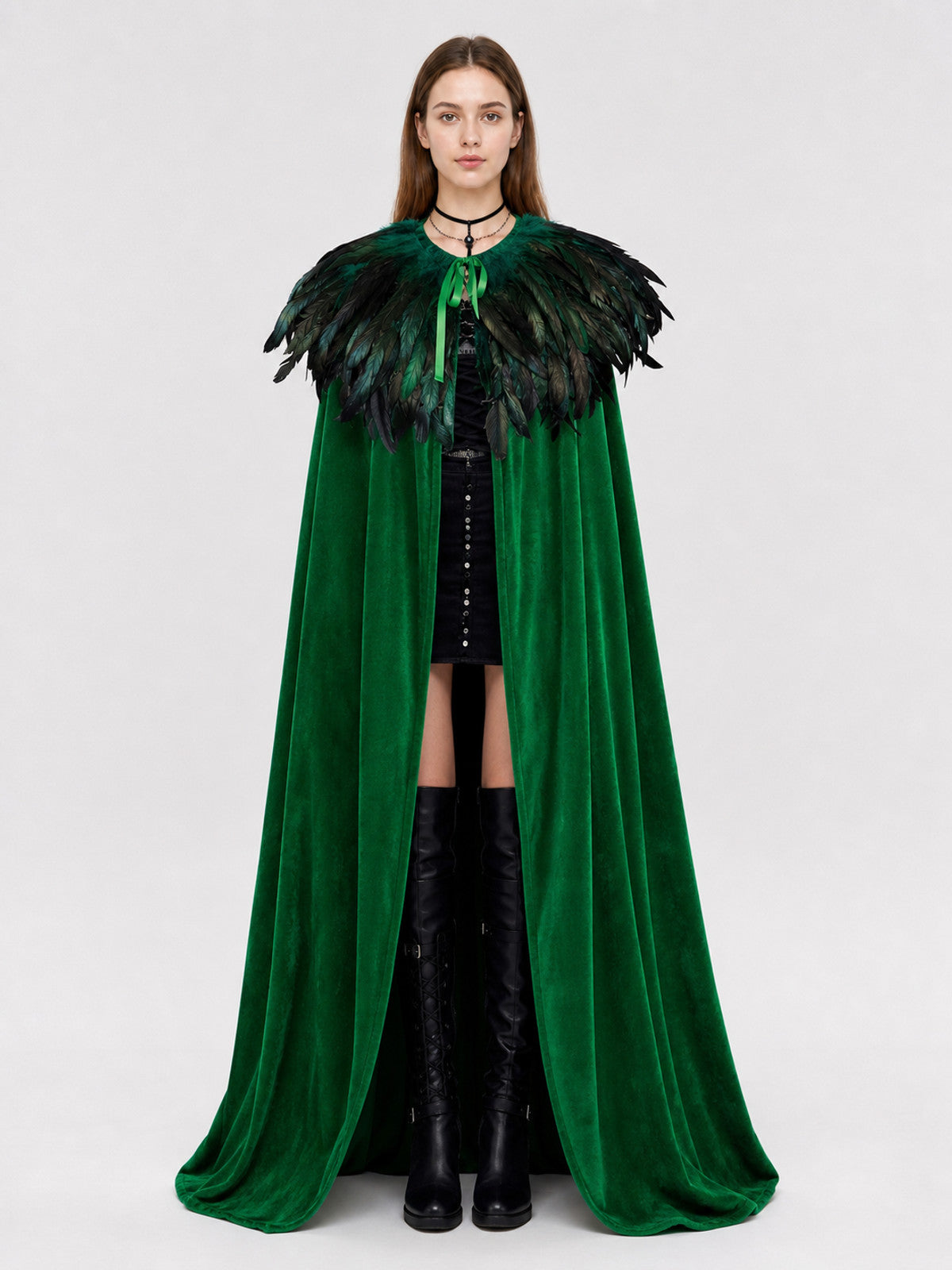 Front view of a green velvet cape on a model with black and green feather trim and a ribbon closure