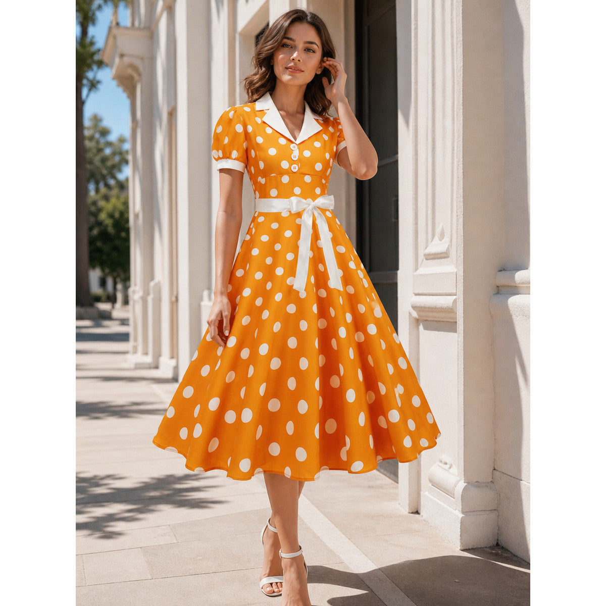 Dress with a White Collar, Bow Belt, and Polka-Dot Print. The dress is designed in an orange-and-white color scheme, with a white polka-dot pattern on an orange background across the upper portion and skirt. A white Peter Pan collar and sho