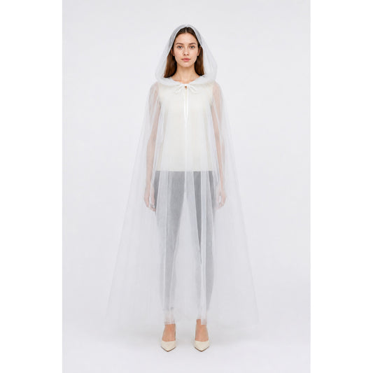 Model wearing the long ivory sheer hooded cape over a white outfit, front view