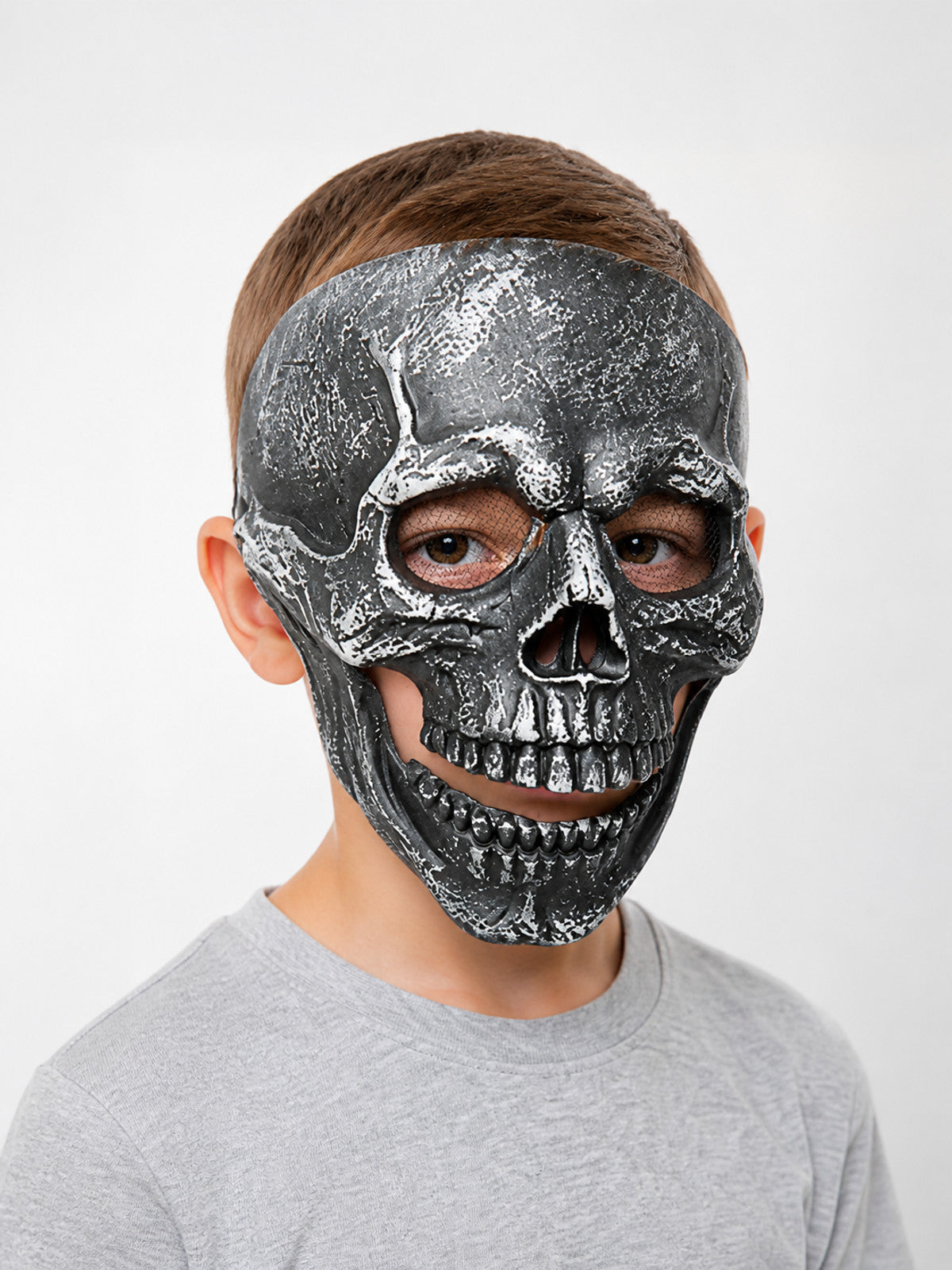 Black skull face mask with metallic textured finish, hollow eye openings, nose cavity and molded teeth, shown close-up on a model