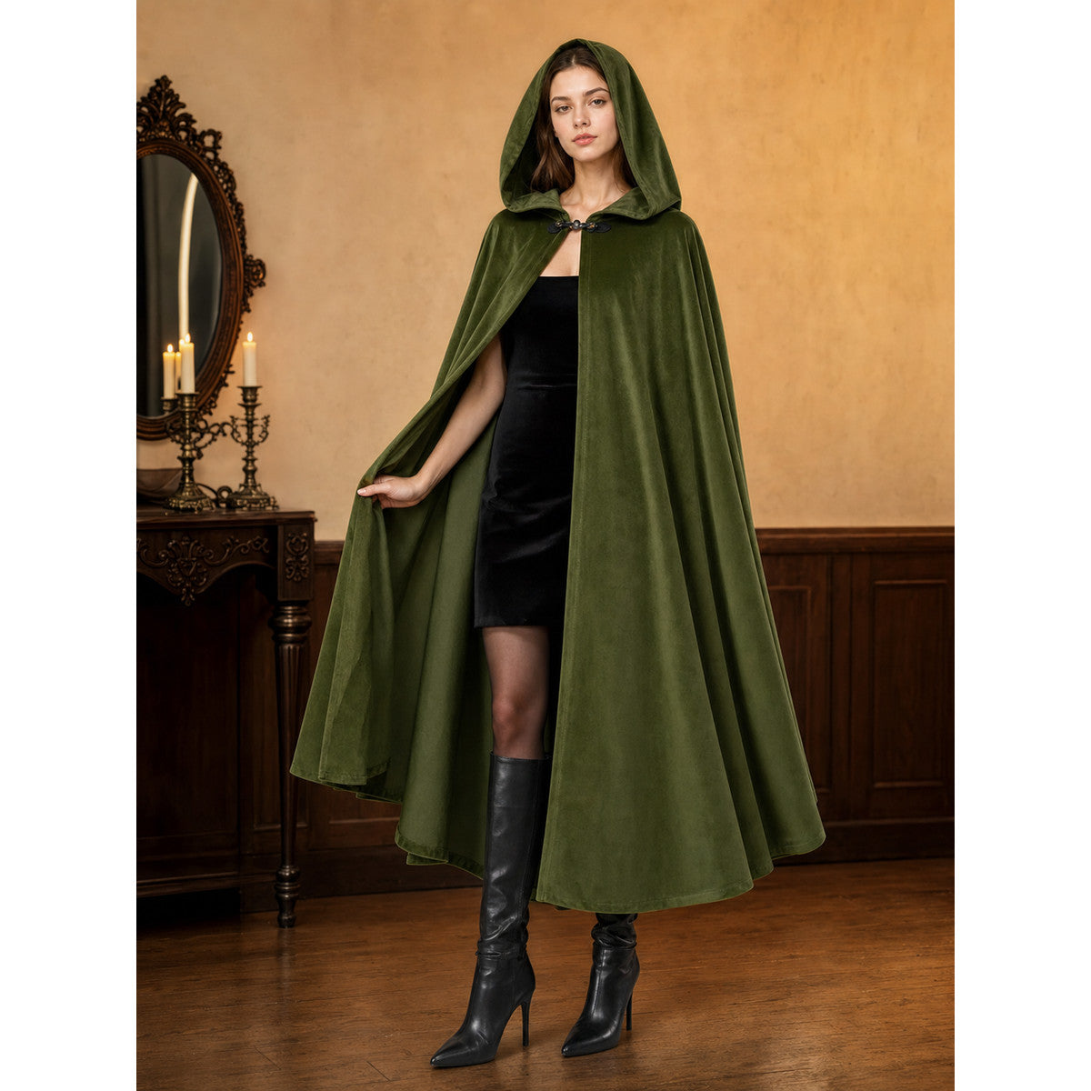 Green velvet-look hooded cloak shown full-body on a model in a dark styled room