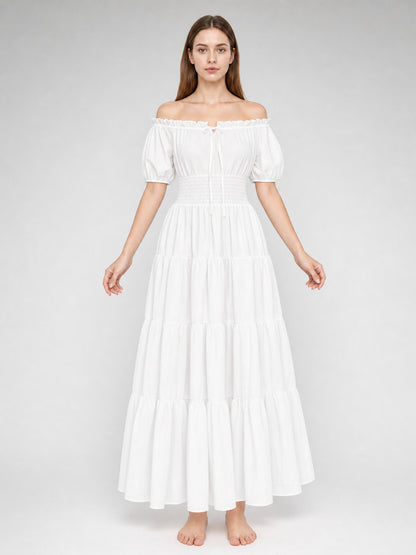 White lightweight-looking off-shoulder maxi dress on a full-body model, with short puff sleeves, a smocked waist, and tiered floor-length skirt