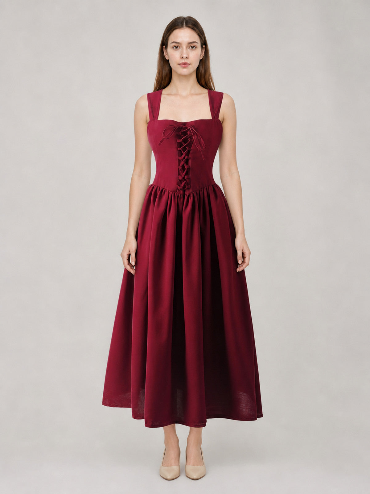 Burgundy long dress with square neckline, wide straps, front corset lacing, gathered waist, and full flowing skirt on a full-body model