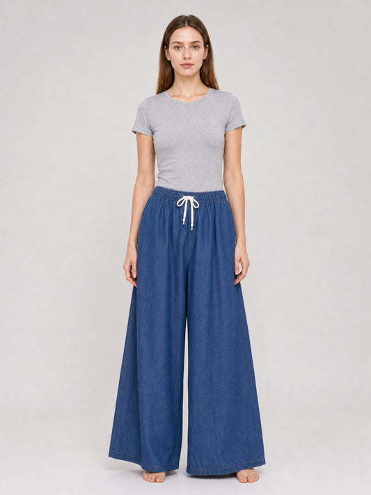 Dark blue wide-leg pants on a full-body model, with an elastic waistband, white drawstring, and bare feet