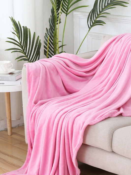 Light pink coral fleece throw blanket draped over a beige sofa
