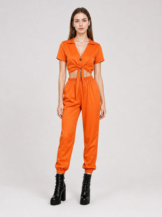 Orange two-piece set with a collared tie-front top and elastic-cuff jogger pants, shown full-body on a woman