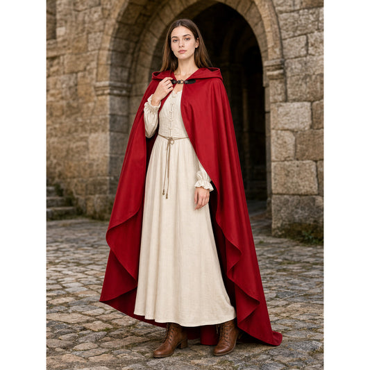 Red hooded cloak with layered edges, shown full-body on a model over a cream dress in front of a stone archway