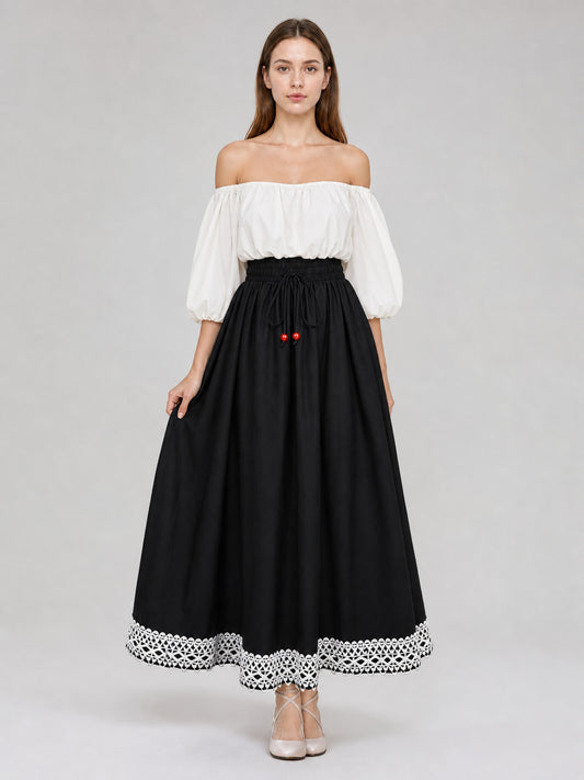 Full-body model wearing a black floor-length skirt with a gathered waist, red bead drawstrings, and white lace trim at the hem