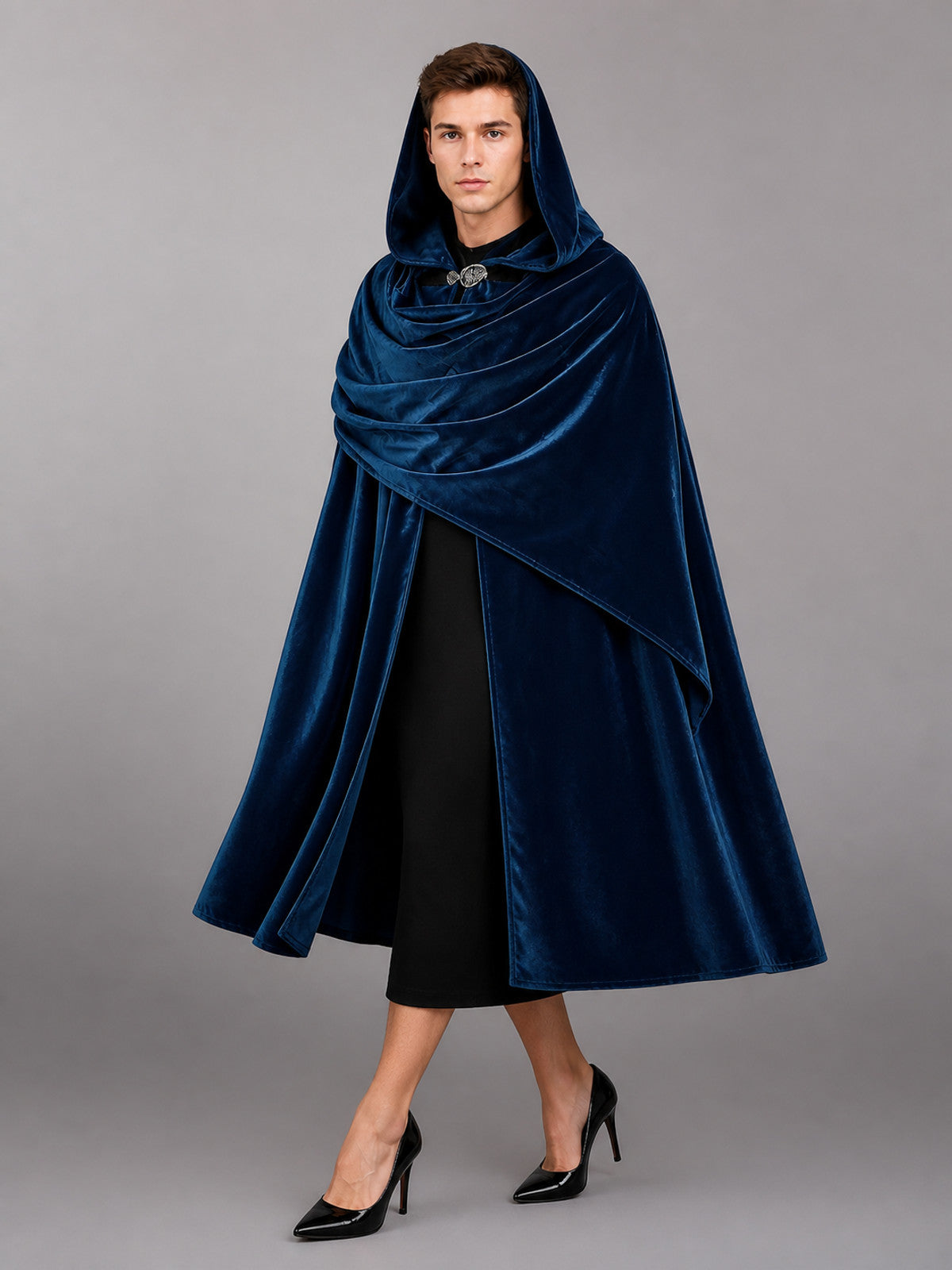 Dark blue velvet-look hooded cloak shown full-length on a model, with draped front panels and a decorative clasp