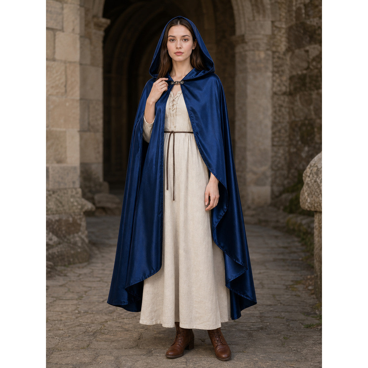 Blue satin-look hooded cape worn full-body over a cream dress, with a front clasp and draped pointed hem