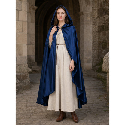Blue satin-look hooded cape worn full-body over a cream dress, with a front clasp and draped pointed hem