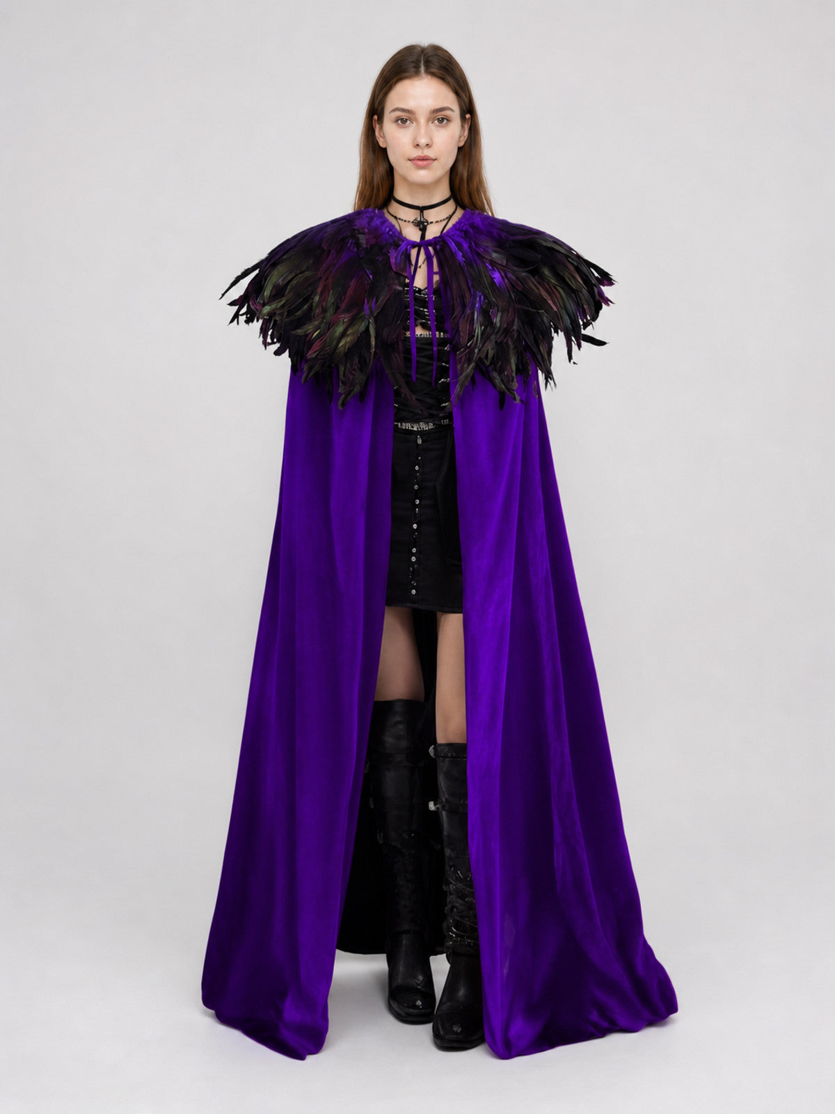 Purple velvet-look costume cape with black feather shoulder trim, shown full-body on a model against a gray studio background