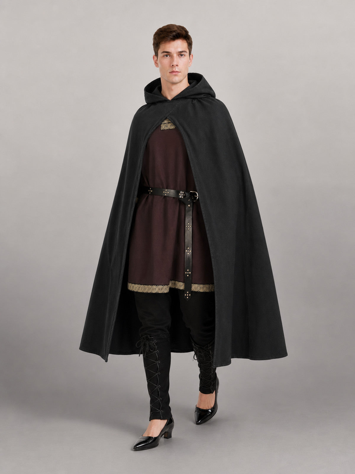 Black hooded cloak in matte fabric shown full-body on a model, worn over a brown tunic with belt and black leggings