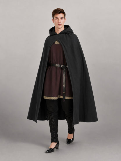 Black hooded cloak in matte fabric shown full-body on a model, worn over a brown tunic with belt and black leggings