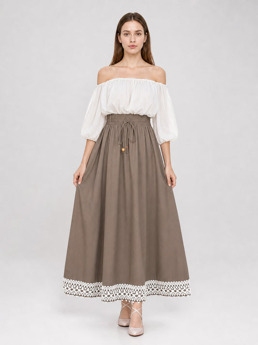 Full-body model wearing a taupe maxi dress with a white off-shoulder gathered top, puff sleeves, drawstring waist, and white lace hem