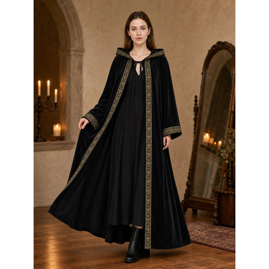 Black hooded cape with gold patterned trim, shown full-body on a model in a candlelit room
