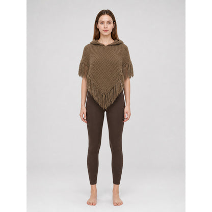 Brown knitted hooded cape with triangular front and fringe, shown full-body on a model against a light gray background